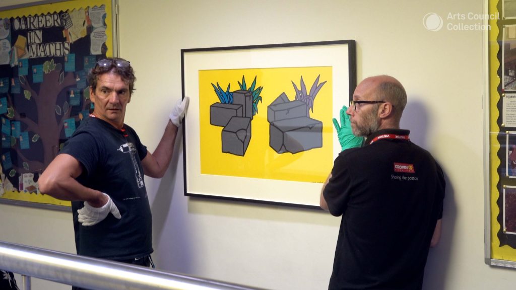 men installing artwork in school